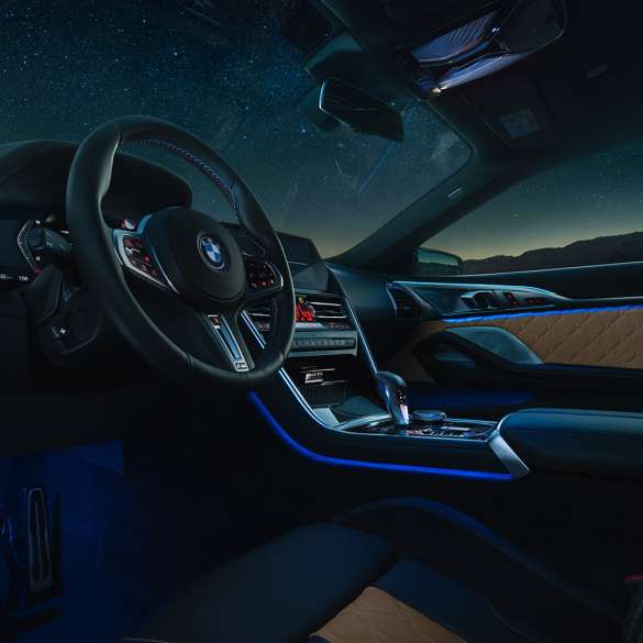 BMW M8 Competition Coupé, cockpit. BMW M8 Competition Coupé, cockpit at night with M leather steering wheel and blue ambient light.