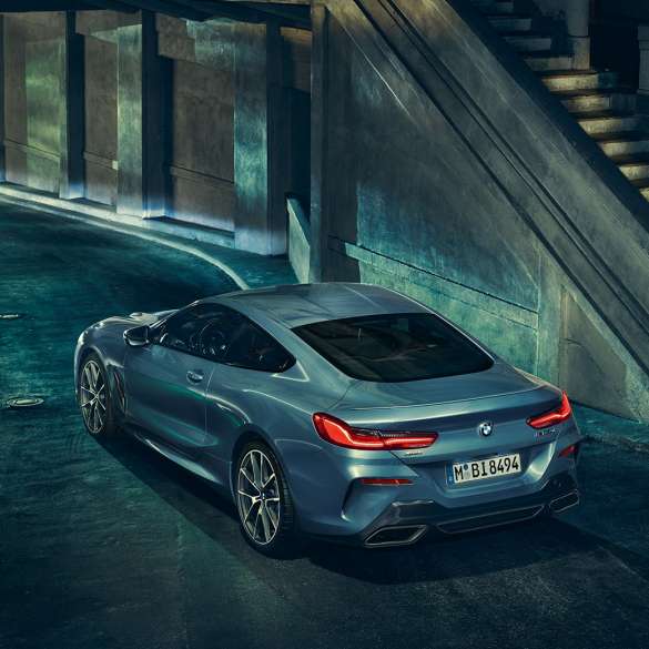 BMW M850i xDrive Coupé, three-quarter rear view left. BMW M850i xDrive Coupé in Barcelona Blue metallic, three-quarter rear view left, standing at night.