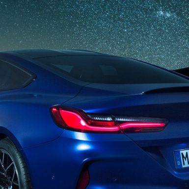 M rear spoiler BMW M8 Competition Coupé in Marina Bay Blue metallic, nightly close-up of shoulder section with M rear spoiler in Carbon.