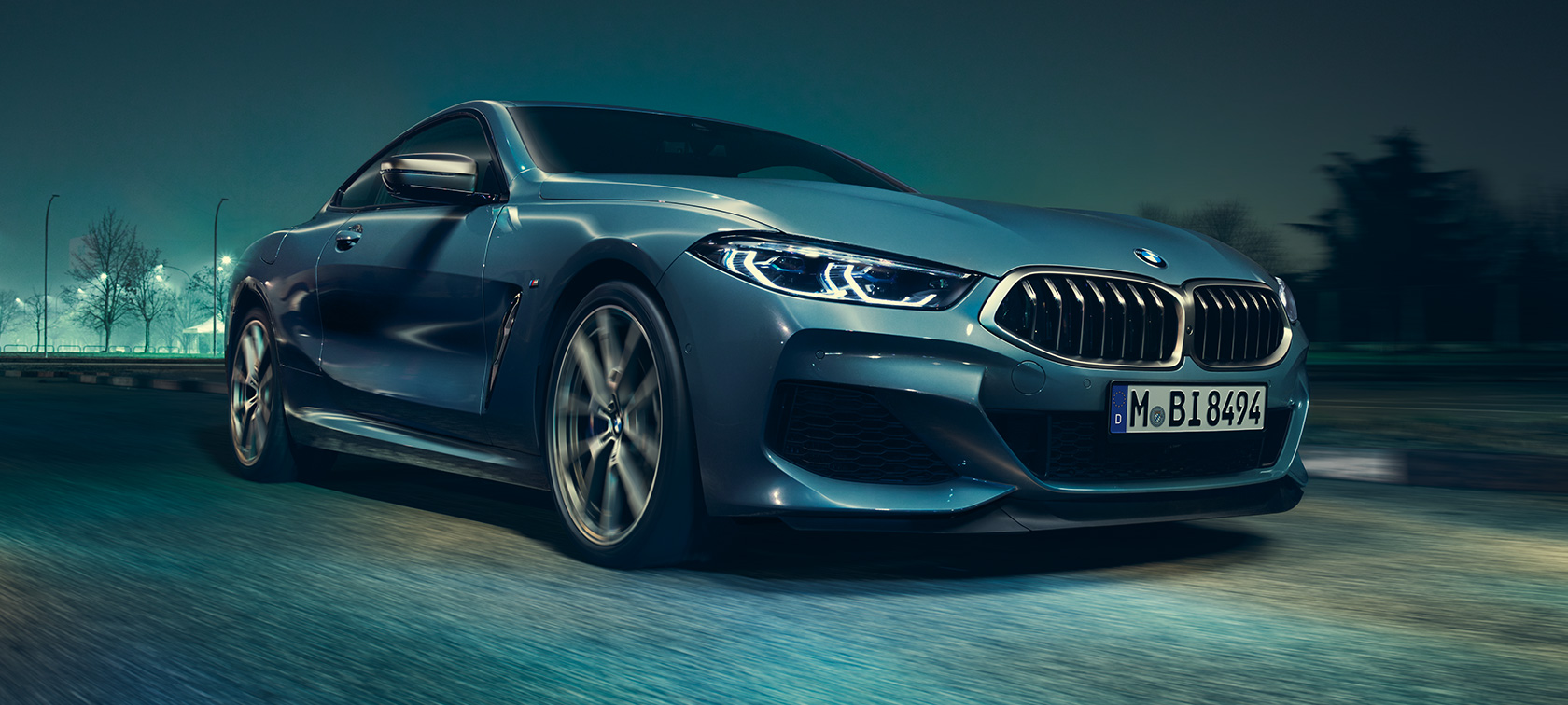 BMW M850i xDrive Coupé, three-quarter front view. BMW M850i xDrive Coupé in Barcelona Blue metallic driving, three-quarter front view.