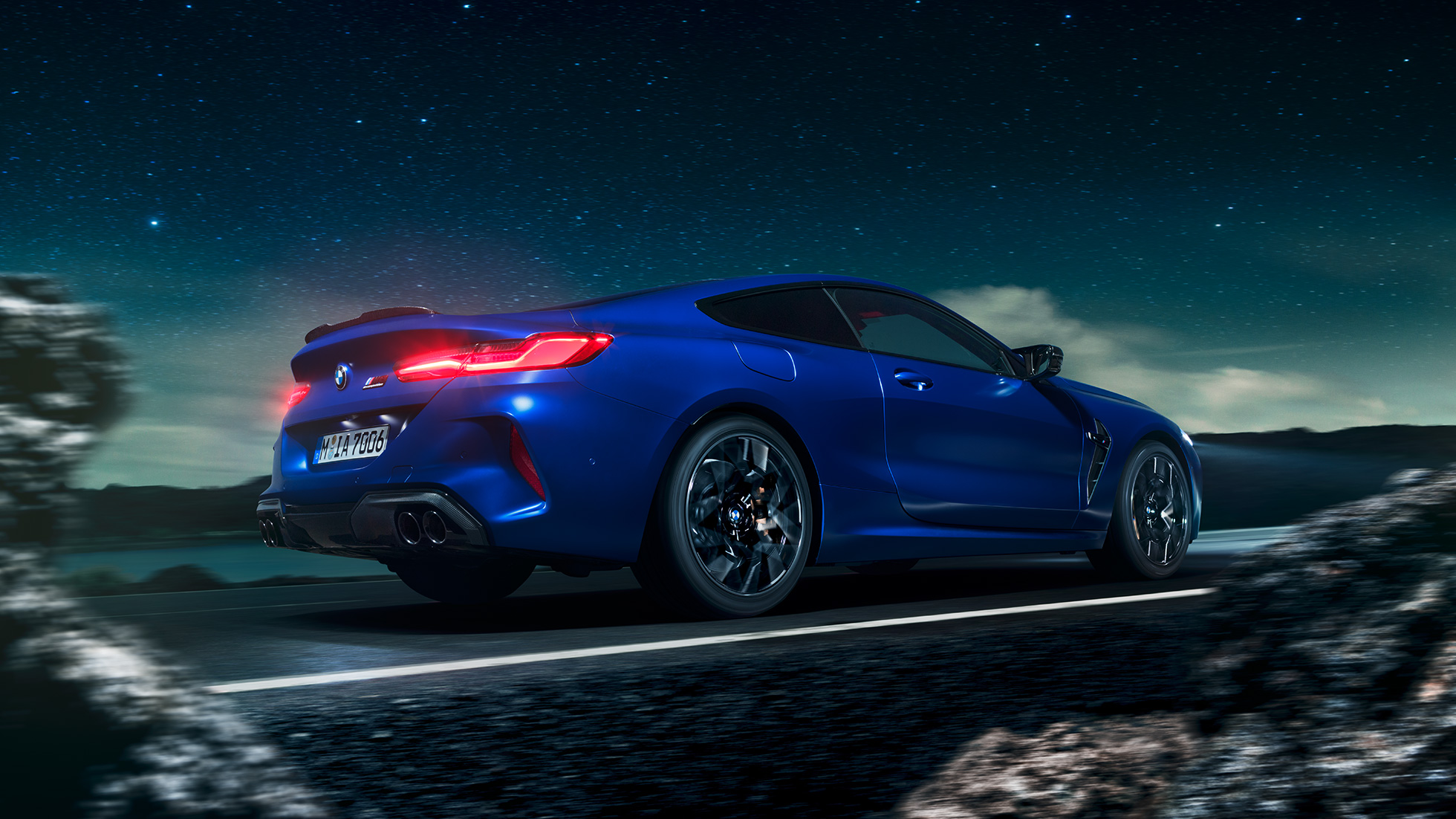 BMW M8 Competition Coupé, three-quarter side view. BMW M8 Competition Coupé in Marina Bay Blue metallic, driving three-quarter side view in front of starry sky.