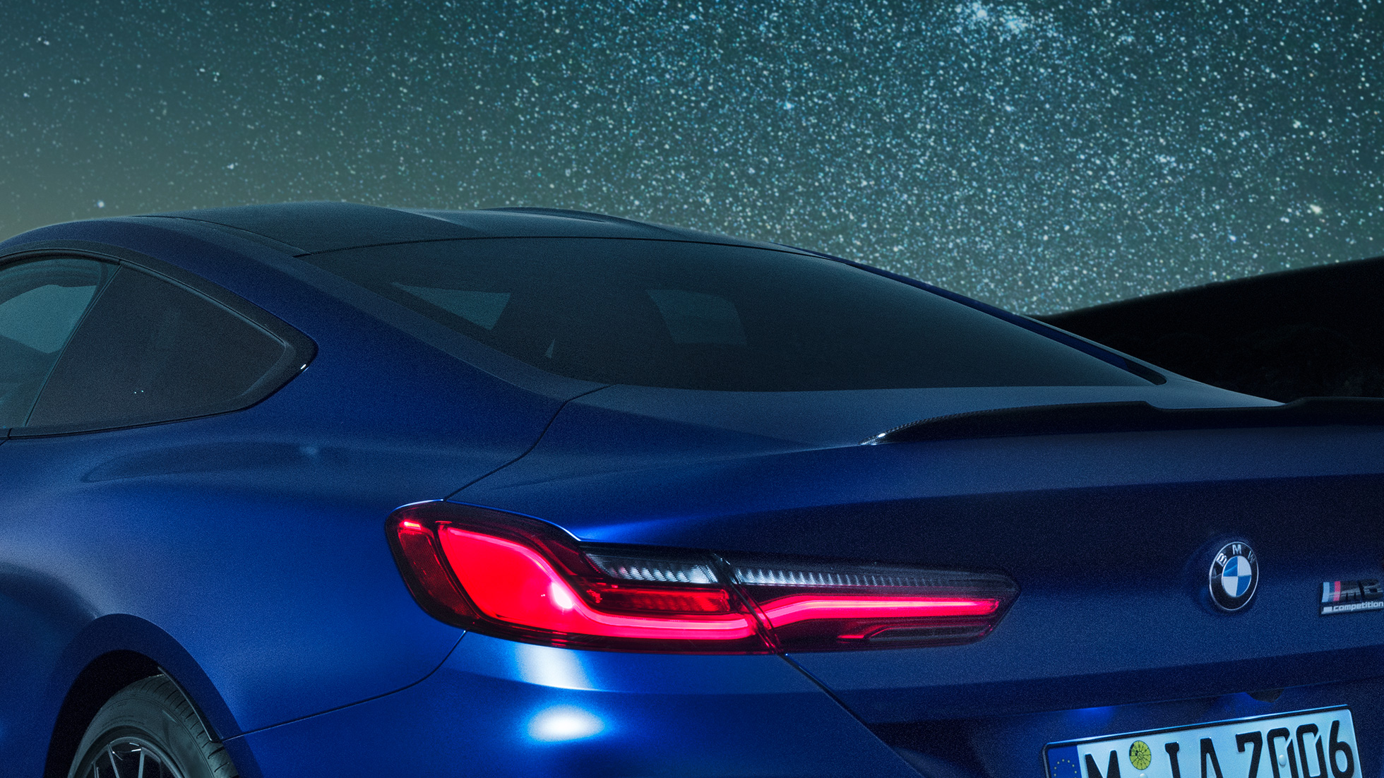 M rear spoiler BMW M8 Competition Coupé in Marina Bay Blue metallic, nightly close-up of shoulder section with M rear spoiler in Carbon.