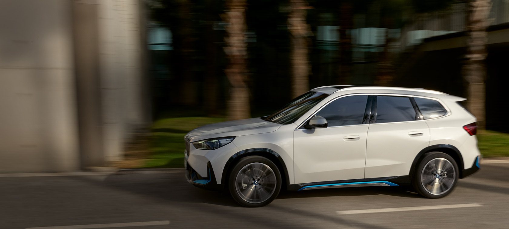 BMW iX1 U11 BEV 2022 Mineral White metallic three quarter front view serpentine mountain road driving