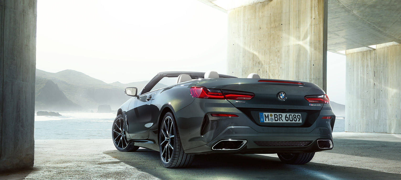 BMW M850i xDrive Dravit Grey metallic, three-quarter view from rear left.