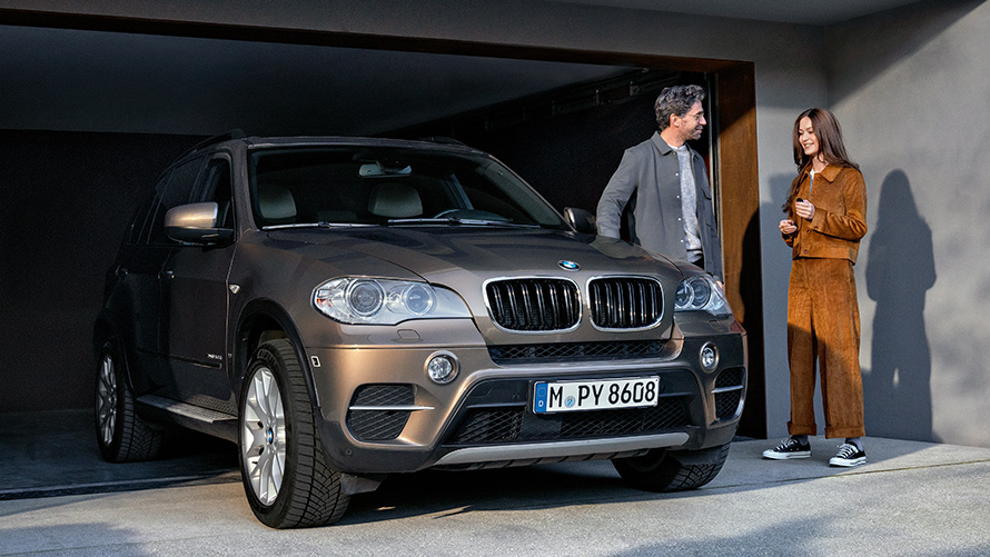 BMW Service BMW Value Service  BMW Value Service man and woman in front of garage with BMW X5