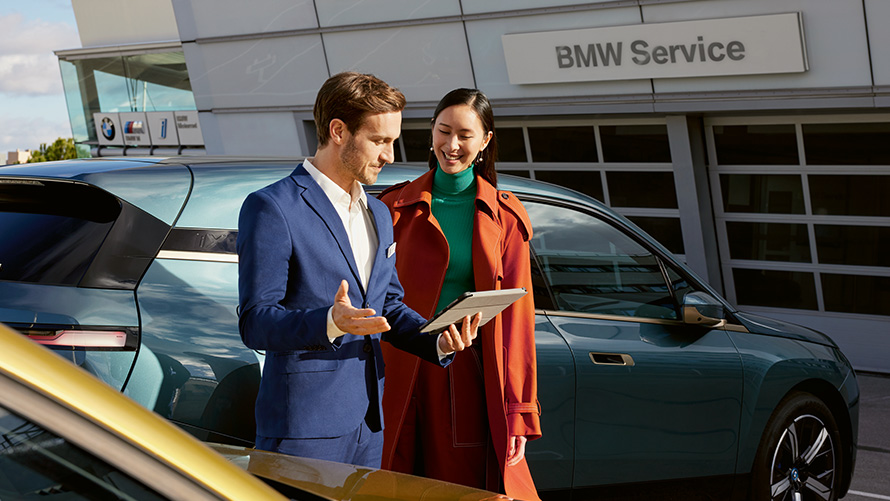 BMW Value Service BMW Service BMW Service man and woman in front of BMW iX at BMW service partner